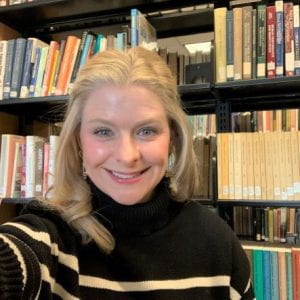 Dana Mastroianni smiling with library bookshelves behind her